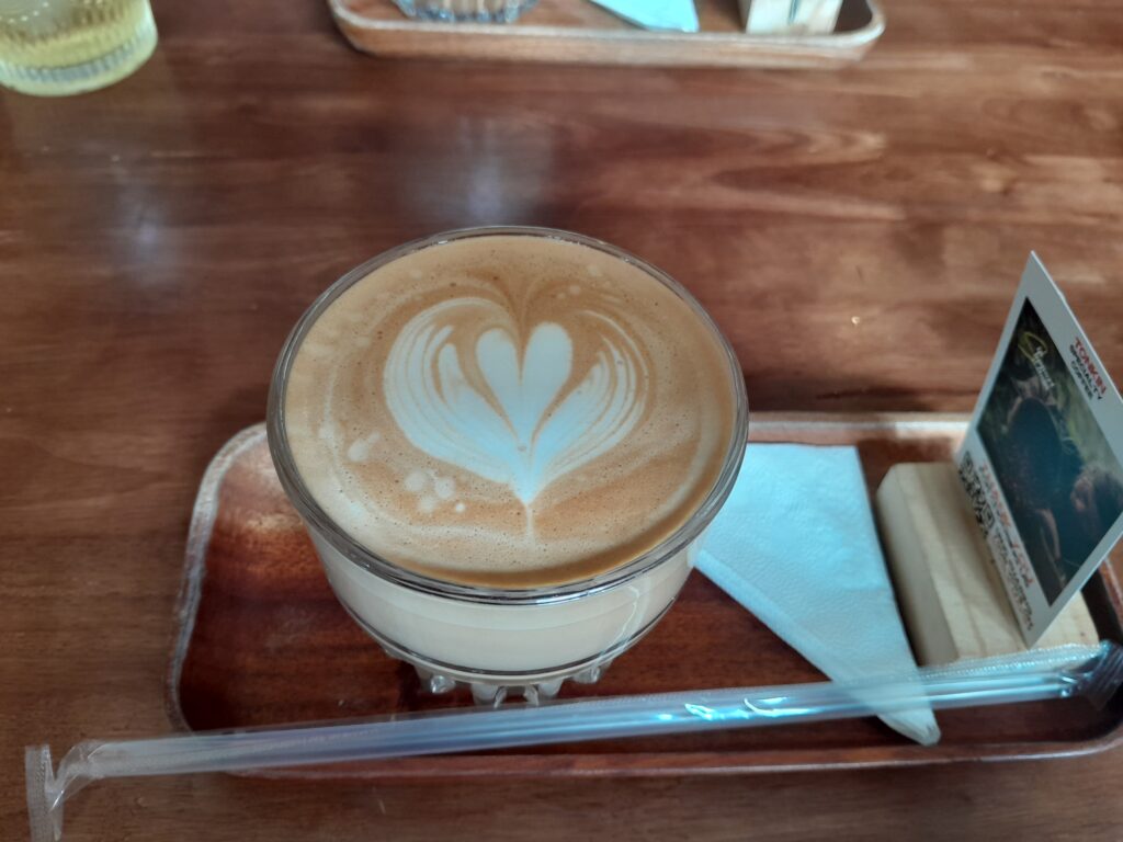 A hot latte in a glass with a straw.